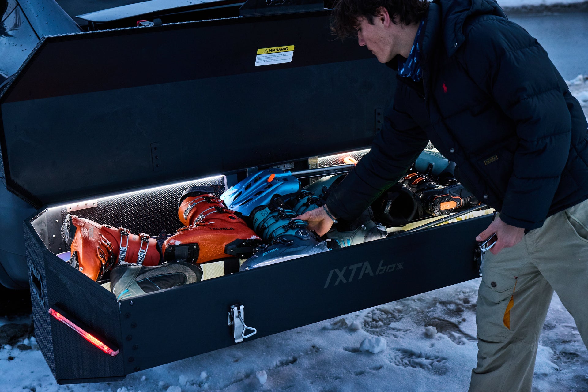Geöffnete IXTAbox mit Skiausrüstung und Handschuhen in verschneiter Winterlandschaft